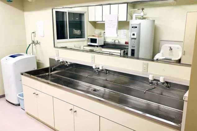 寮の居室にあるクローゼット（収納）。観音開きのドアを開けた状態の内側で、奥の壁は白く、床はフローリング。