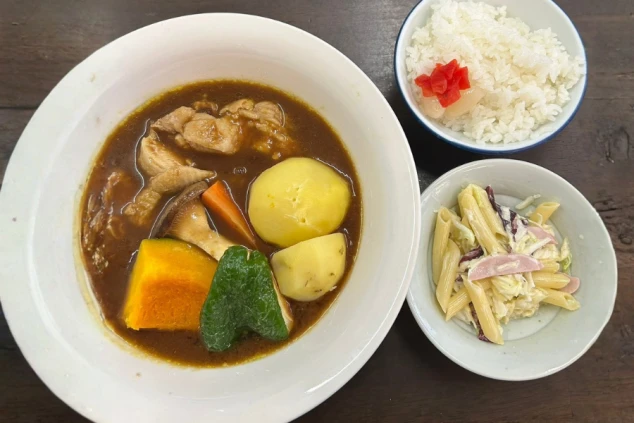 大きめの具材が入ったスープカレー、ご飯、マカロニサラダが並ぶ充実した食事風景。