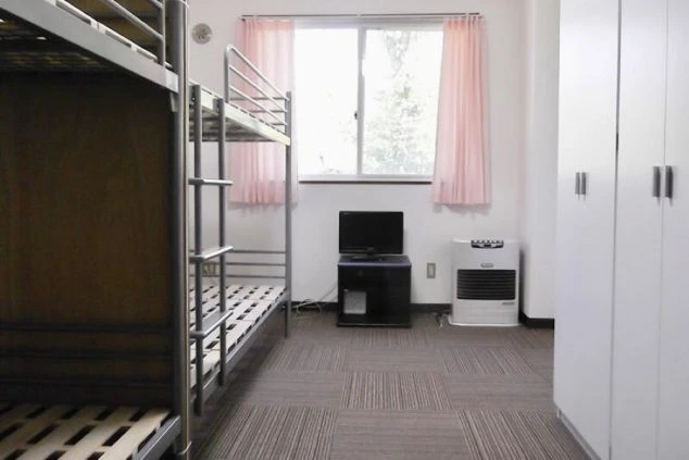 リゾートバイト相部屋寮の部屋の画像。TVと暖房器具がある。