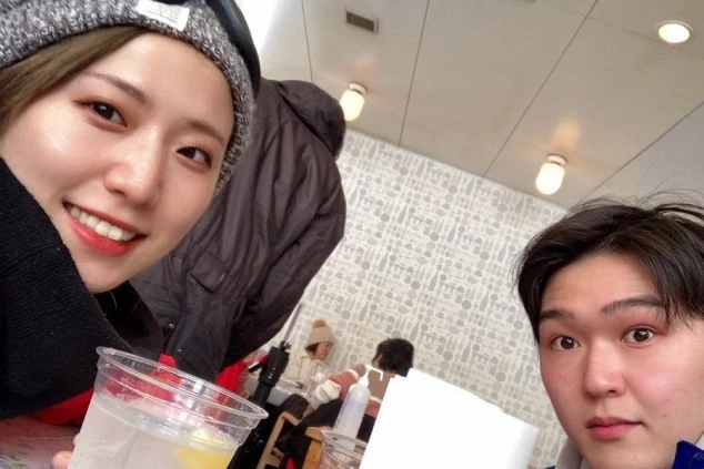 スキー場のレストランで休憩中に、笑顔で自撮りをする男女。