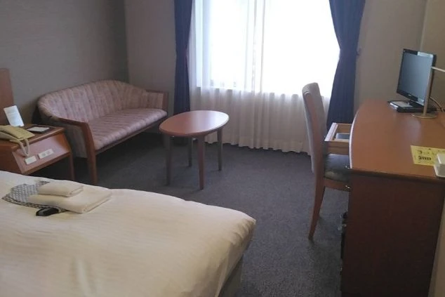 リゾートバイトの客室寮(個室)の全体画像。ベッド、デスク、ソファ、テレビが揃ったホテルの充実した設備。