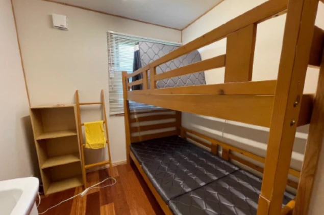 寮の相部屋。二段ベッド、収納棚、洗面台が映る部屋の様子。