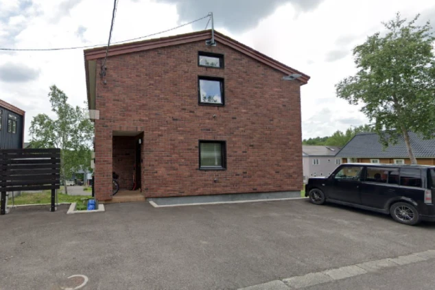 寮の外観。レンガ調の壁と黒い窓が映るモダンな建物。