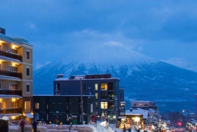 雪に覆われた街並みと、奥にそびえる羊蹄山が映る冬の夜景のイメージ画像。リゾートバイトの休日を満喫。