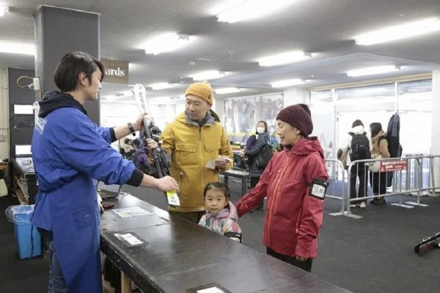 スキー場のレンタルショップで、スタッフから用具の説明を受ける家族。子供連れでも、安心してレンタルできる。