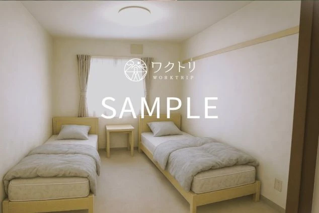 ワクトリ提供の2人用の相部屋寮の寝室。シングルベッドが2台置かれ、友人やカップルでのリゾートバイトに最適な、プライベートが確保された部屋のシェアの寮のサンプル画像。