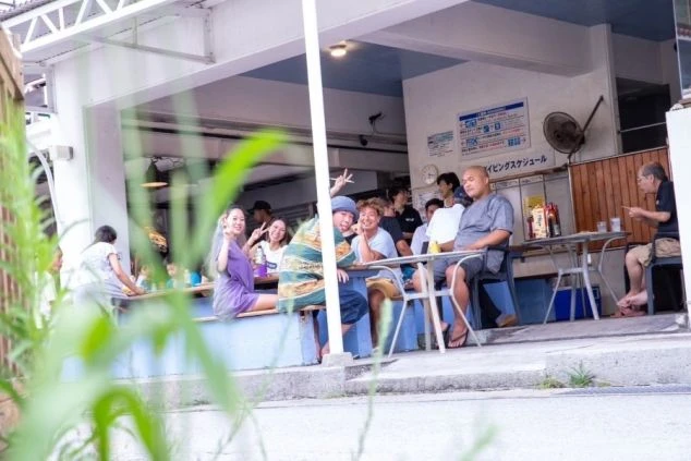 飲食店で食事を楽しむ友人たち。テラス席に座って、カメラに笑顔やポーズを見せている。