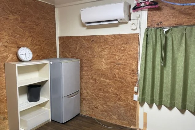 寮の居室。冷蔵庫や棚、エアコンが備え付けられており、生活に必要なものが揃っている。