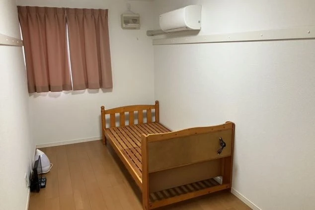 リゾートバイトの女性寮の個室。フローリングの部屋に、ベッドとエアコンが完備されたシンプルなプライベート空間。