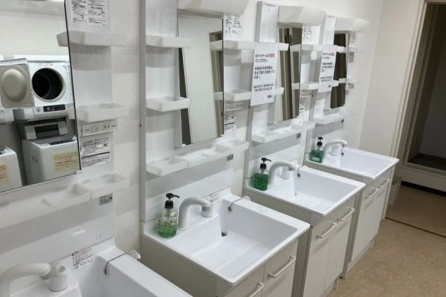 リゾートバイトの女性寮の、清潔な共用洗面所。独立洗面台が複数並んでおり、朝の忙しい時間でも快適に利用できる。