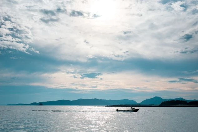 夕暮れの海に、一艘のボートが浮かんでいる画像。リゾートバイトの休日に海辺で穏やかな時間を過ごすイメージ。