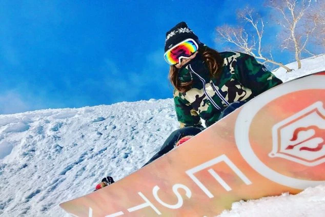 雪山でスノーボードを楽しむ女性。趣味を活かせるリゾートバイトをイメージする画像。