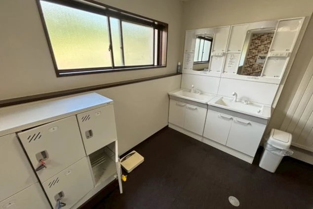 寮の洗面所。鏡付きの洗面台と、私物を保管できるロッカーが並ぶ。リゾートバイトの共同生活を支える設備。