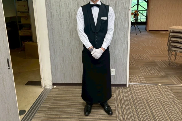 ホールスタッフ(男性)制服。白いシャツに黒のベストと蝶ネクタイで、高級感のあるサービス服。