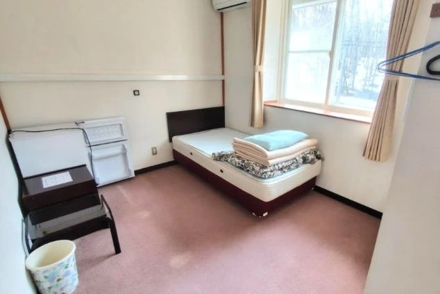 個室内にはベッドや冷蔵庫、テーブル、ゴミ箱が設置されている。