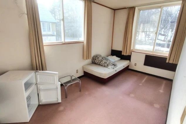 個室内にはベッド、冷蔵庫、テーブルが設置されている。