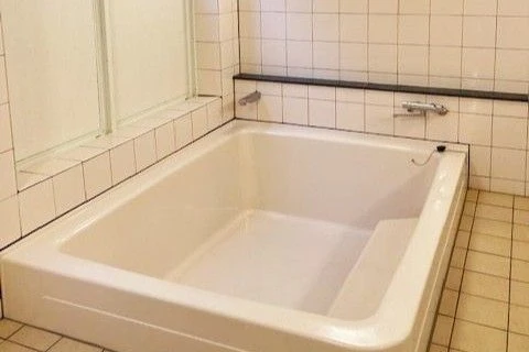 寮の共同浴場。広々とした大きな浴槽で、タイル張りの壁が清潔感を保っている。