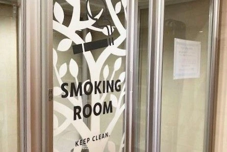 「SMOKING ROOM」と書かれた喫煙室のドア。寮内にある共用スペース。