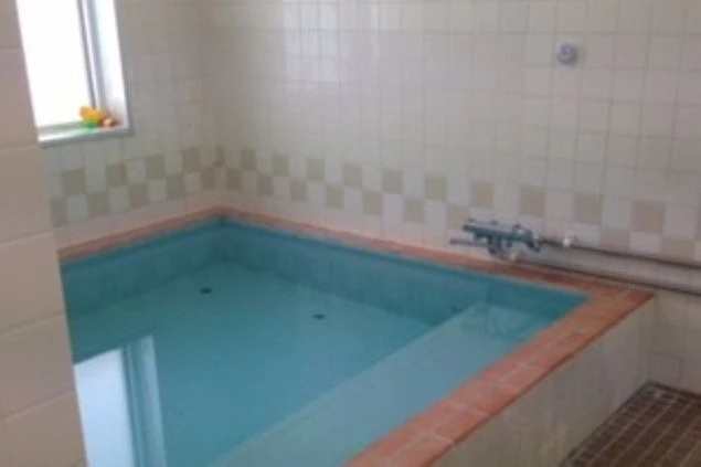 寮の大浴場。タイルの壁と広い湯船が映る清潔な共同浴場。