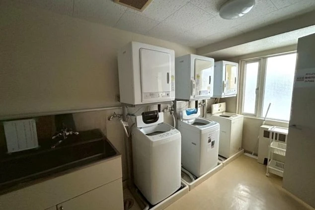 寮内のランドリールームの画像。全自動洗濯機と衣類乾燥機がセットで複数台設置されている。