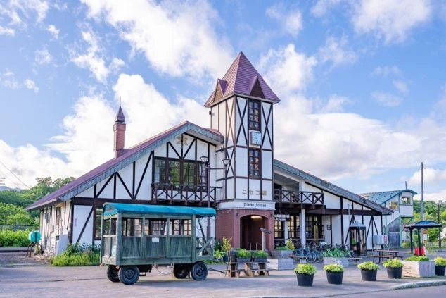 美瑛駅。ヨーロッパ風の可愛らしい駅舎と、緑の幌馬車が映るイメージ画像。リゾートバイトの休日を満喫。