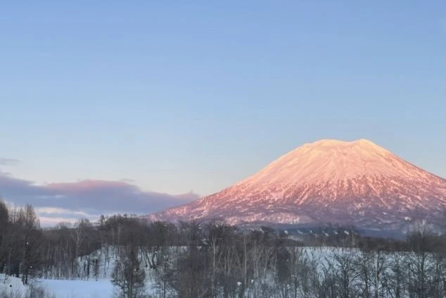 朝焼けに染まる雪山の羊蹄山。雪原と木々が広がる冬の絶景のイメージ画像。リゾートバイトの休日を満喫。