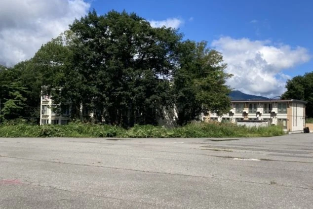 寮の共同浴場の画像。複数のシャワーブースと浴槽があり、ピンク色のタイルが特徴的。リゾートバイト中の入浴設備。