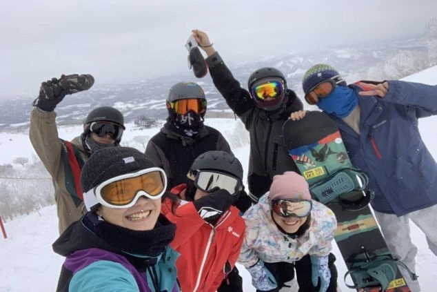 ワクトリのスタッフが撮った雪山で、スノーボードウェアを着た若者たちが集合写真を撮っている画像。リゾートバイトの仲間との絆が楽しめるイメージ。