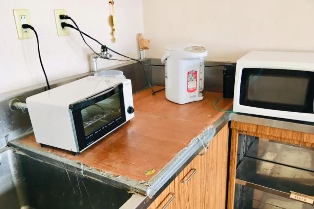 寮のキッチン。シンク、トースター、電気ケトル、電子レンジが並ぶ共用スペースが映る。