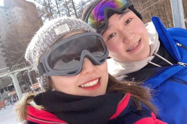 スキー場で、仲良くリフトに乗るカップルの笑顔のセルフィー画像。