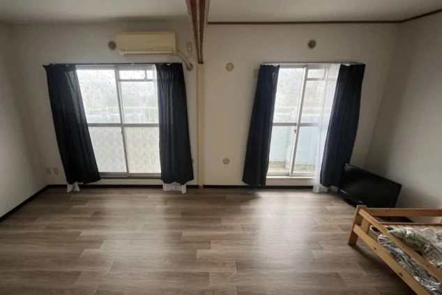 リゾートバイトの寮の個室。フローリングの部屋に、ベランダへ通じる大きな窓があり、日当たりが良い。