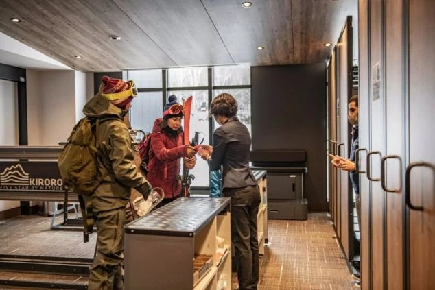 雪山のゲレンデで、スキー客がスタッフにリフト券を提示している画像。リゾートバイトのバレー業務のイメージ。