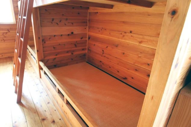 リゾートバイトの相部屋寮の寝室。木の温もりが感じられる二段ベッドで、プライベート空間も確保されています。