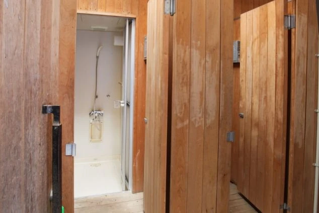 リゾートバイトの寮に完備された共用のシャワールーム。複数の個室があり、木の扉でプライバシーが守られ、清潔に保たれています。