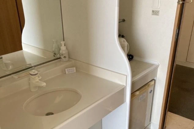 リゾートバイトの相部屋寮に備え付けられた洗面台とミニ冷蔵庫。清潔感のある広い洗面台で身支度ができ、冷蔵庫も利用できるため便利です。