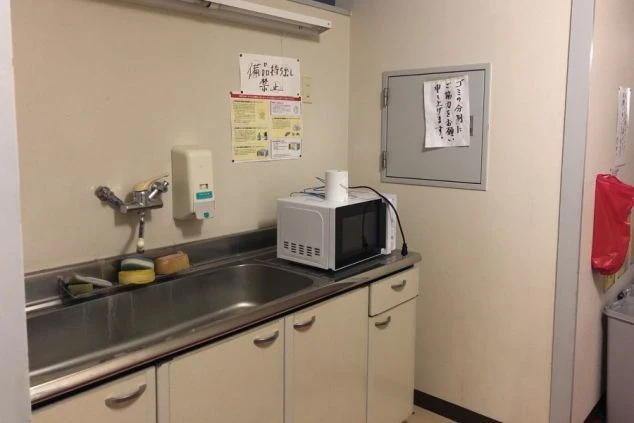 リゾートバイトの寮の共同キッチンの画像。冷蔵庫、電子レンジ、シンクが備え付けられている。