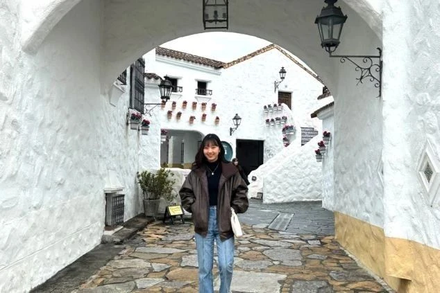 白い壁と石畳が特徴的な、異国情緒あふれる街並みを歩く女性の写真。三重県伊勢志摩などのリゾート地での仕事を通して、まるで海外を旅しているかのような非日常的な体験を楽しめることを表現しています。