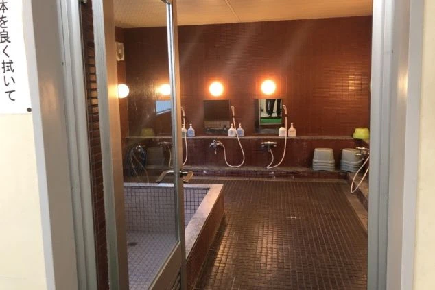 リゾートバイトの寮の大浴場の画像。広々とした湯船と洗い場がある。