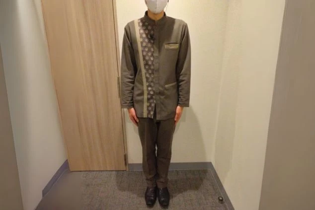 グレーと茶色を基調とした制服画像。制服の胸元には黒い模様の入った生地が縦に入っている。ホテルや旅館でのベル・フロントスタッフの制服の画像。