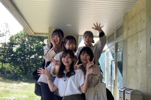 リゾートバイトの寮の前で、笑顔でピースサインをする6人の女性たち。新しい仲間との出会いや、充実した寮生活を送りたい方に魅力的なワクトリスタッフが撮影したオリジナル画像。