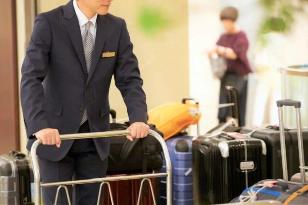ホテルのベルスタッフが荷物を運んでいる様子。「ベル staff」の文字が重ねられ、リゾートバイトでベルスタッフやフロント業務に興味がある方に訴求するワクトリオリジナル画像。