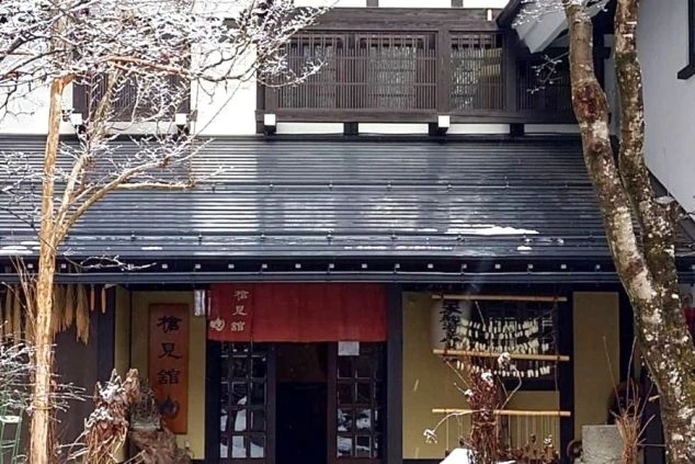 雪が薄く積もった、伝統的な日本の旅館」の玄関。