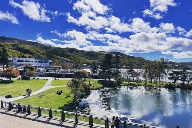 青い空と雲の下、白樺湖とリゾート施設、緑の芝生が広がる風景。リゾートバイトで湖畔のホテルやレジャー施設で働きたい方に訴求する画像。