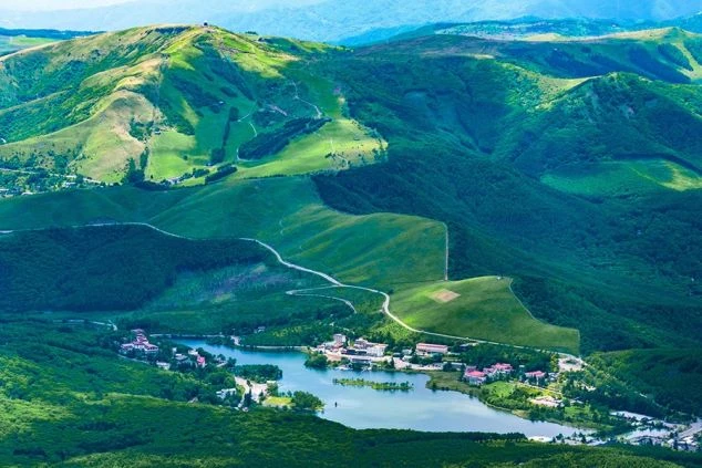 長野県白樺湖と周辺のリゾート施設を上空から見た風景。緑豊かな山々に囲まれた湖畔の景色で、リゾートバイトで自然を満喫しながら働きたい方に訴求する画像。