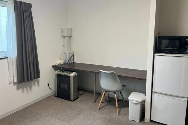 リゾートバイトの寮の個室に備え付けられた、広々とした机。冷蔵庫や電子レンジ、暖房器具も揃っている。