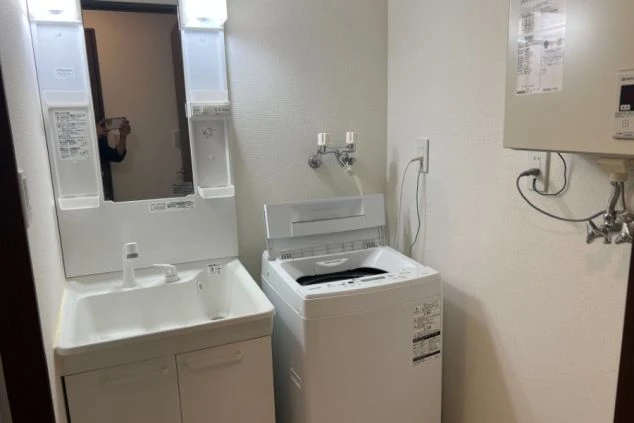 リゾートバイトの寮の、清潔な洗面所と洗濯機置き場。独立洗面台と洗濯機が室内にあり、快適に生活できる。
