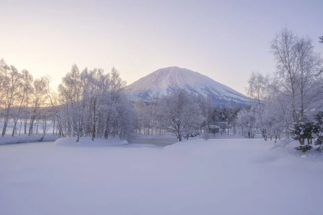 雪に覆われた街並みと、その奥に雄大な羊蹄山がそびえる画像。リゾートバイトで壮大な雪景色が楽しめる魅力。