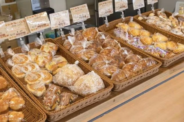 カゴにたくさんのパンが並べられた、パン屋の売店。リゾートバイトでパン職人や販売スタッフとして働き、美味しそうなパンに囲まれたい方に魅力的な画像。