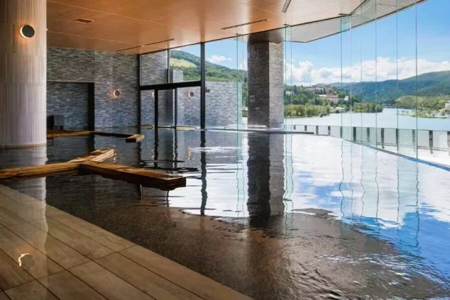 白樺湖の絶景が一望できる、リゾートホテルの内風呂。窓から光が差し込み、水面には空が反射している、リゾートバイトで温泉地での仕事と癒やしを両立したい方に魅力的な画像。