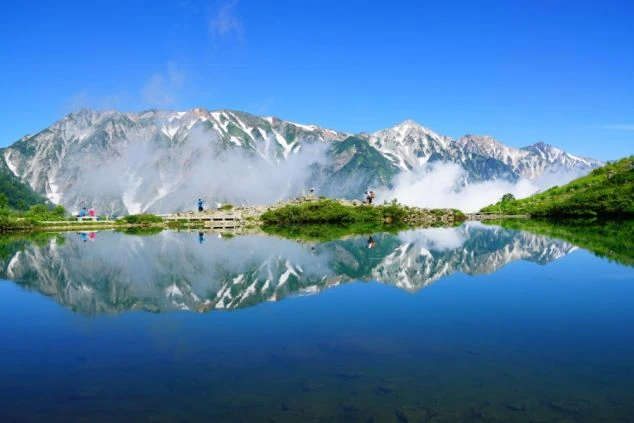 青い空と雪解けの山々を映し出す、長野県白馬村・八方池の画像。